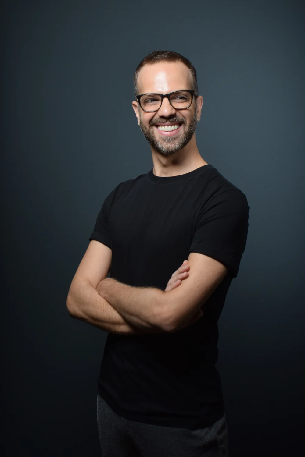 Bruno sorrindo de braços cruzados